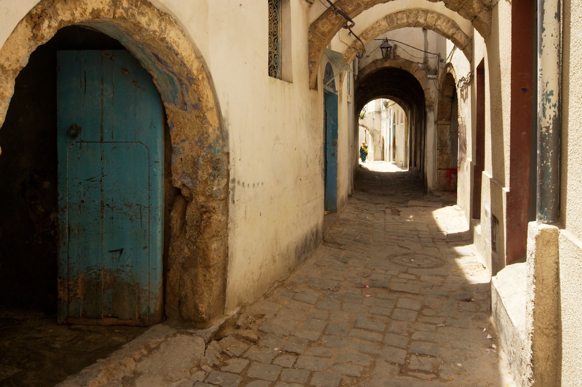 An arched alleyway with a blue door in the medina of Bizerte, Tunisia — navigating the ancient streets