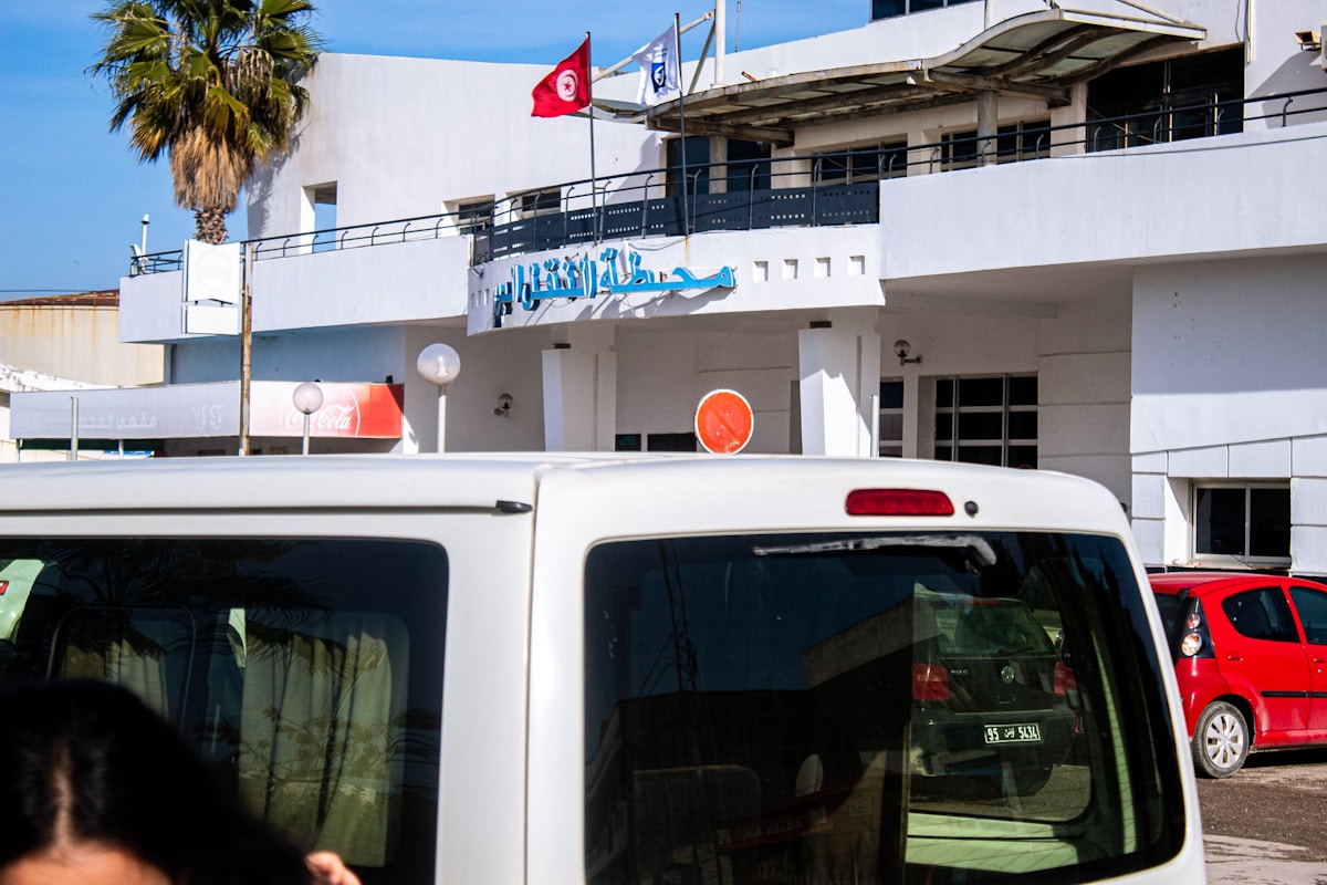 Un van louage devant une station en Tunisie avec le drapeau tunisien