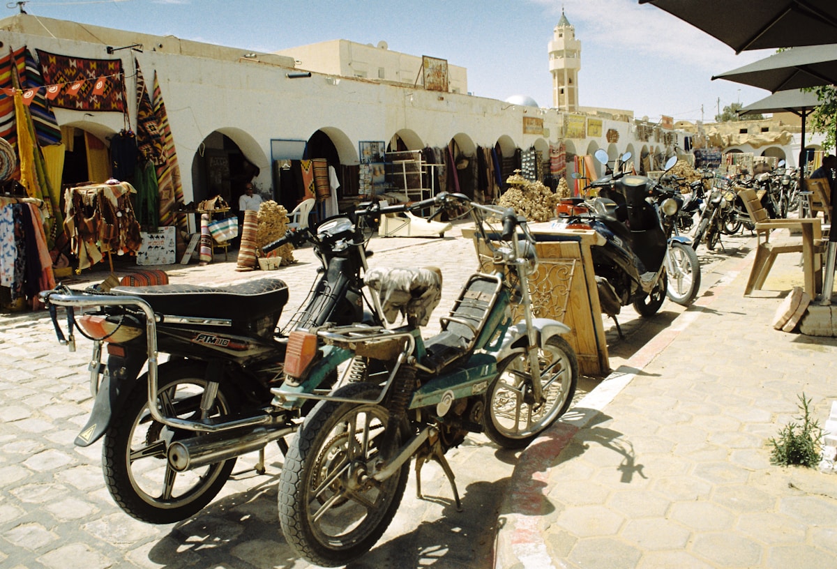 Rue animée avec motos et boutiques dans une médina tunisienne — guide sécurité et arnaques