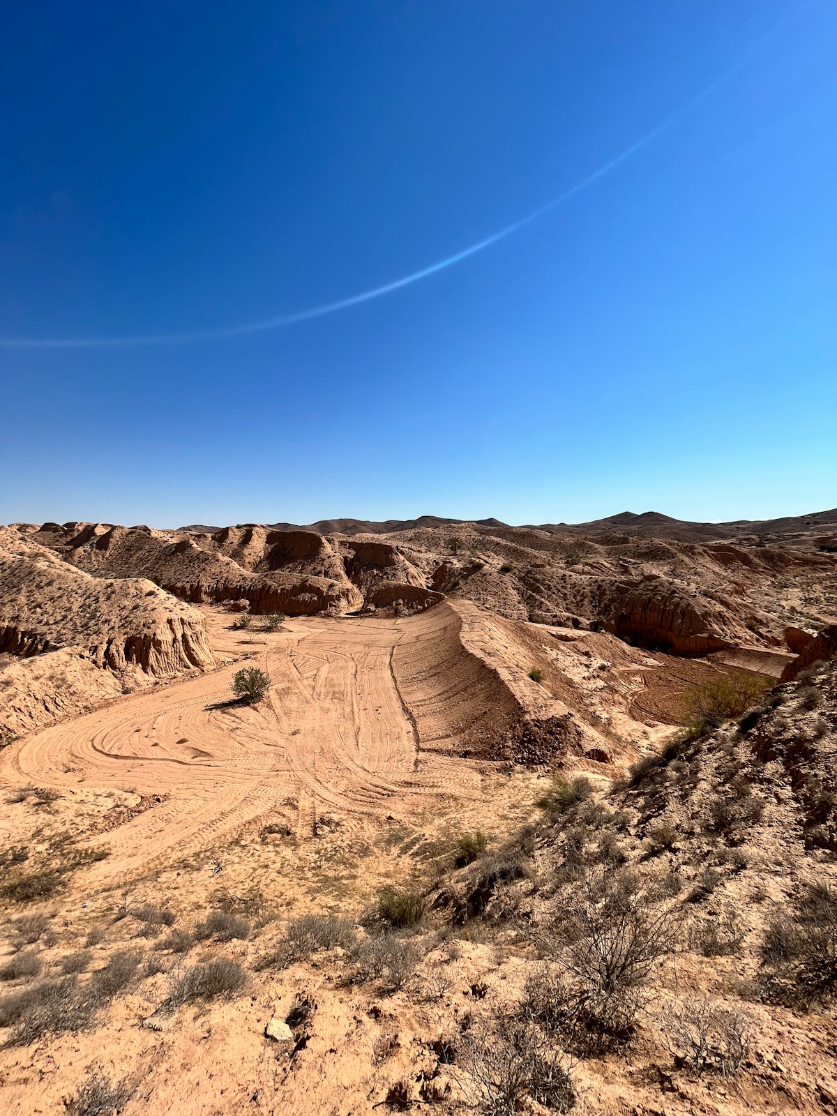 Arid desert landscape with sandy ravines and blue sky near Douz, the gateway to the Sahara, Tunisia